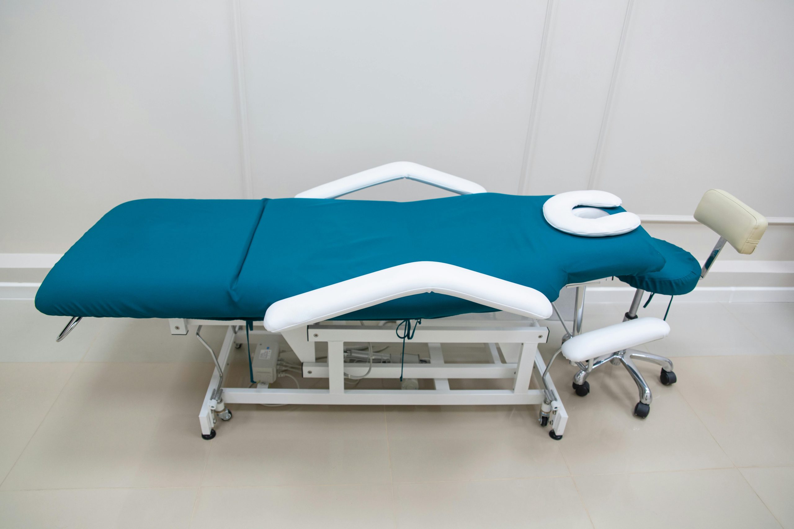 pexels photo 7789609 7789609 A sterile and adjustable medical examination table with a teal mattress in a clinical setting.